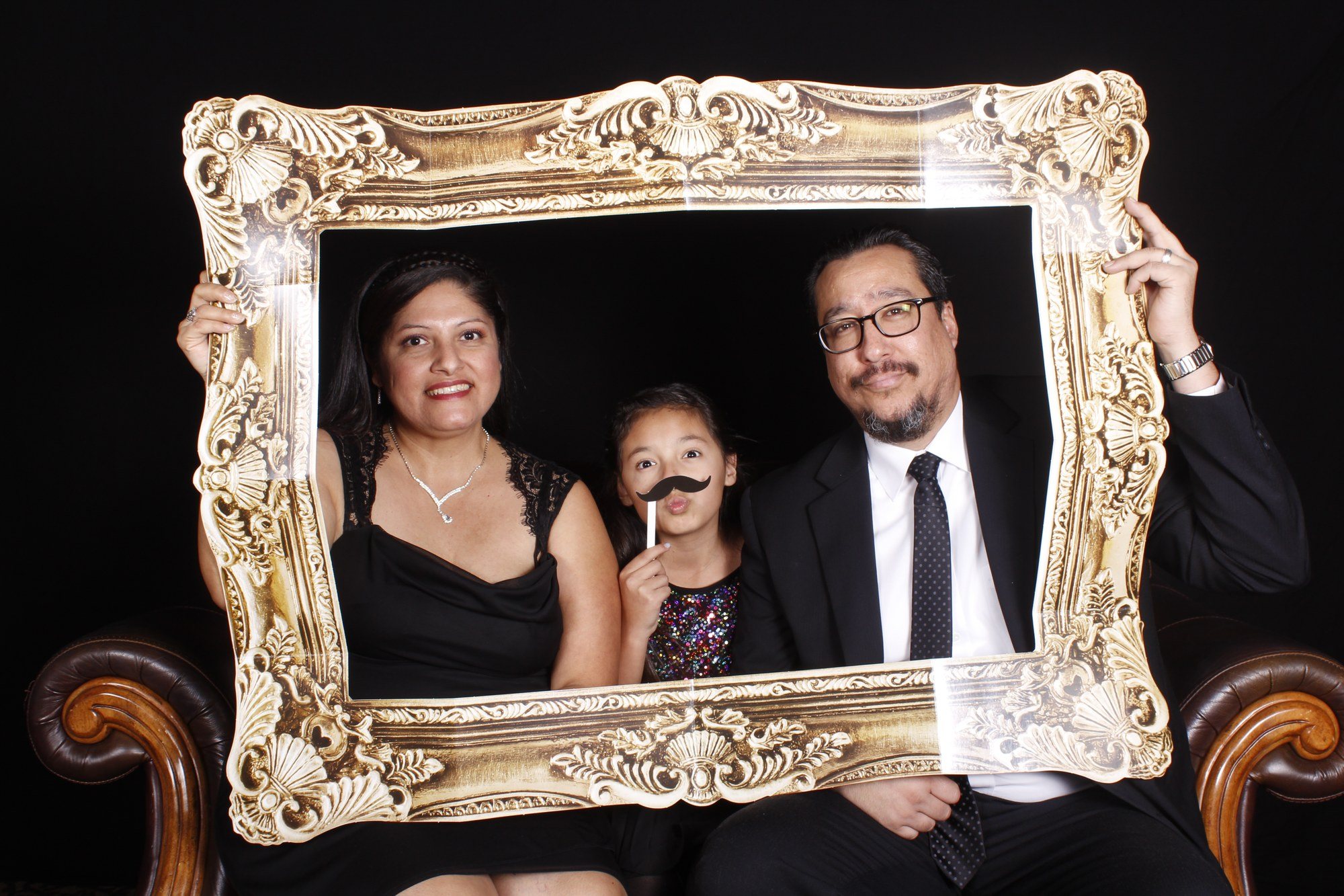 Guests posing with a gold frame prop in the open-air photo booth