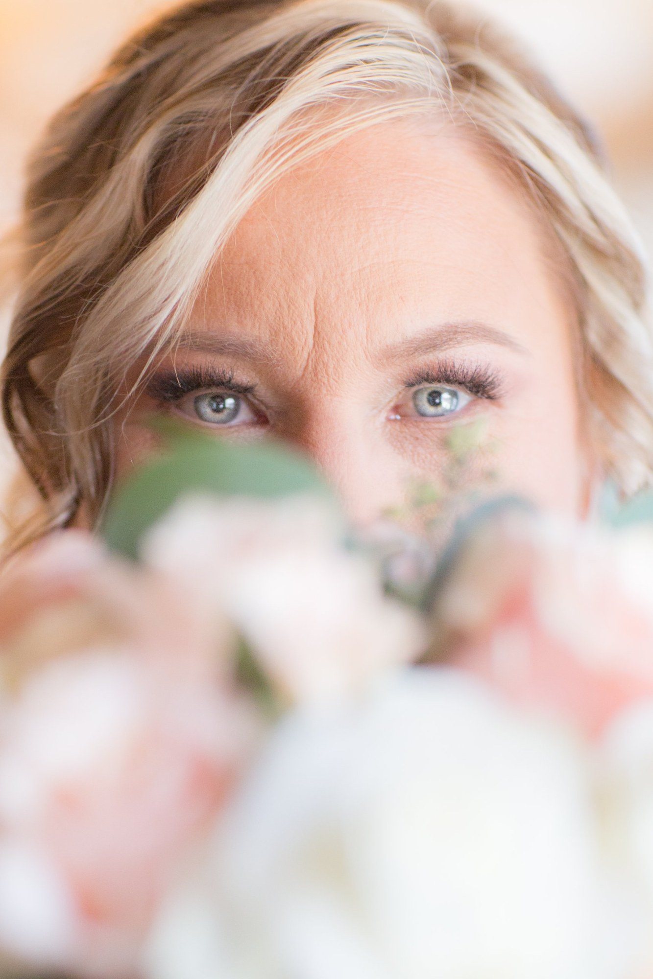 Bride's blue eyes looking over her blush bouquet