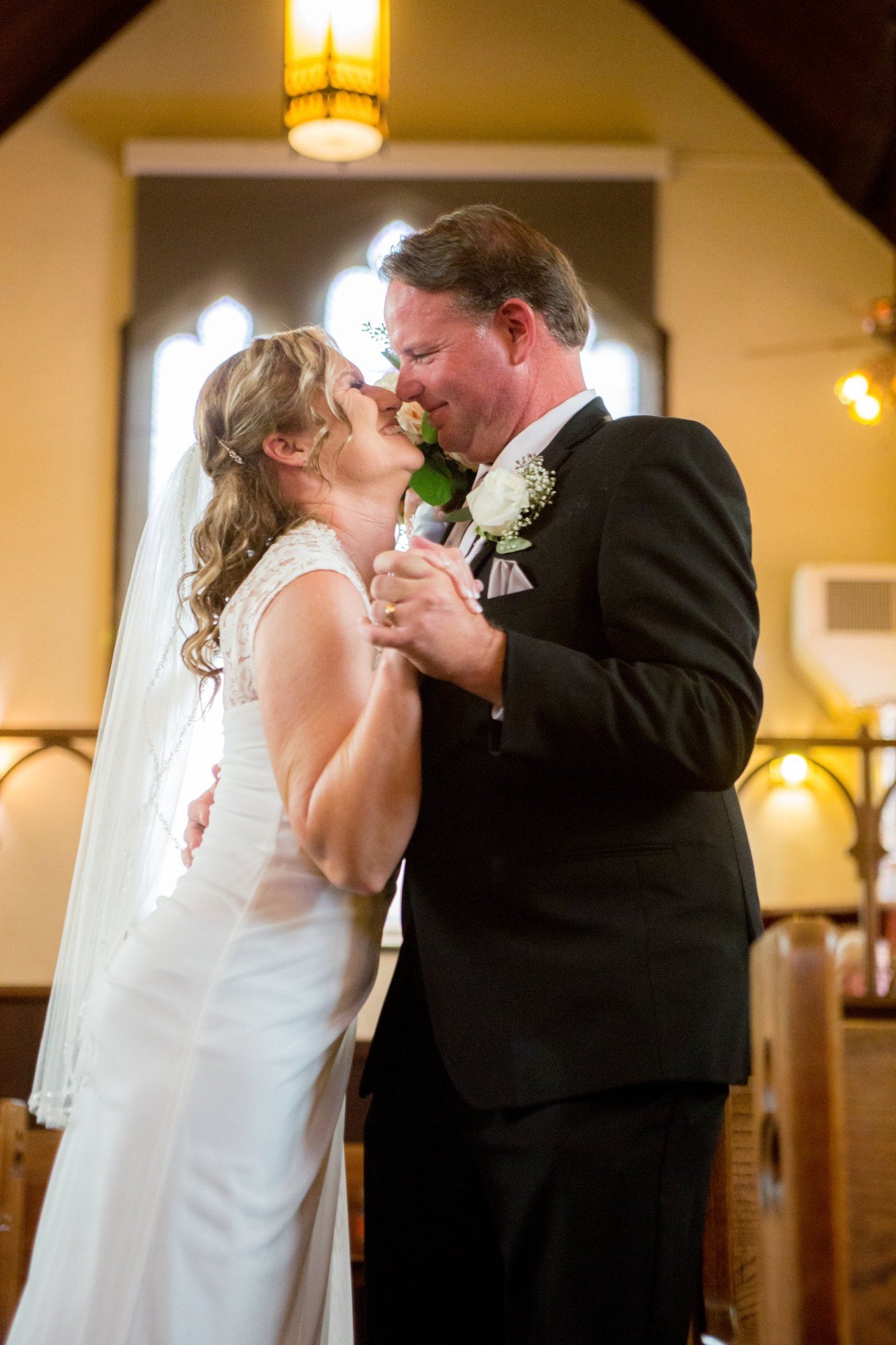 Newlyweds nose to nose in a sunlit chapel