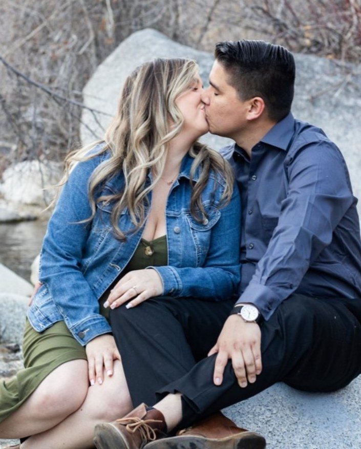 Engaged couple kissing on a granite boulder