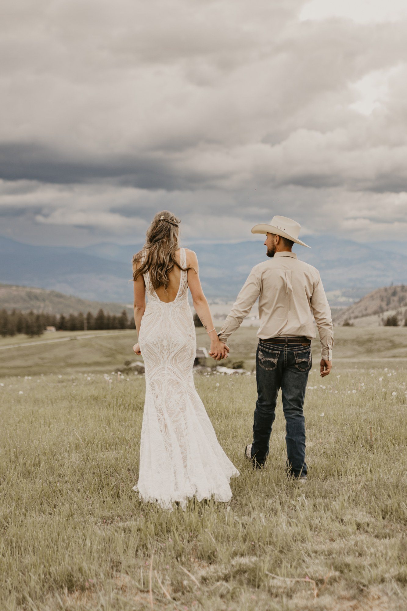 Bride and groom walking away hand in hand toward the mountains