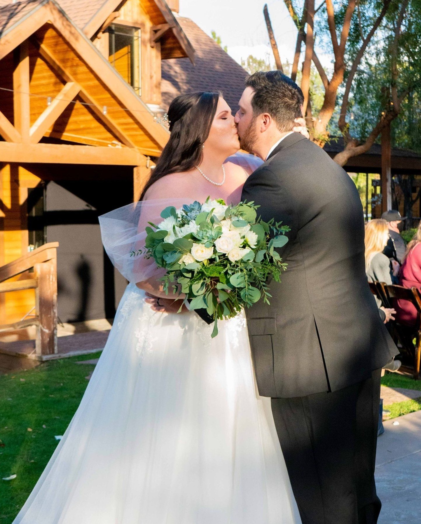First kiss at the end of the aisle outside a timber lodge