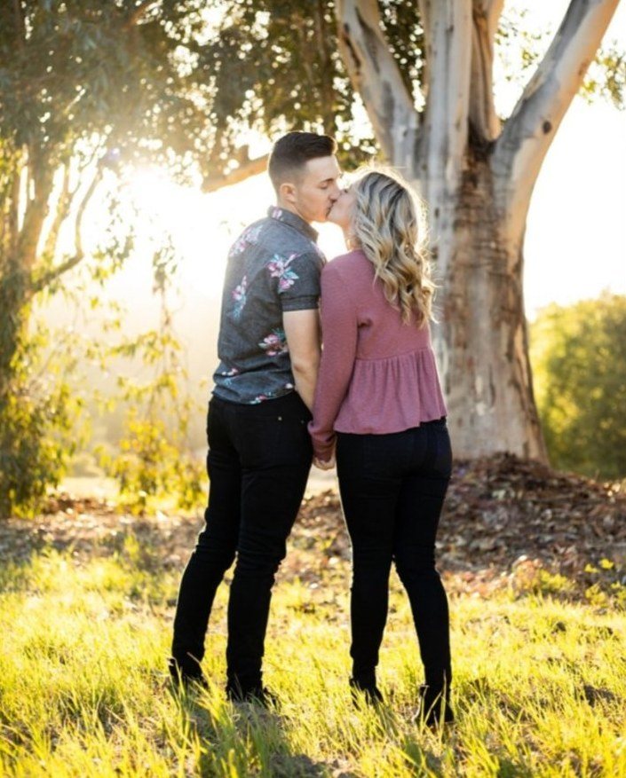 Couple kissing under a eucalyptus tree in golden light