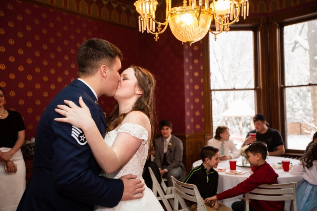 Newlyweds kissing during their reception in a historic dining room