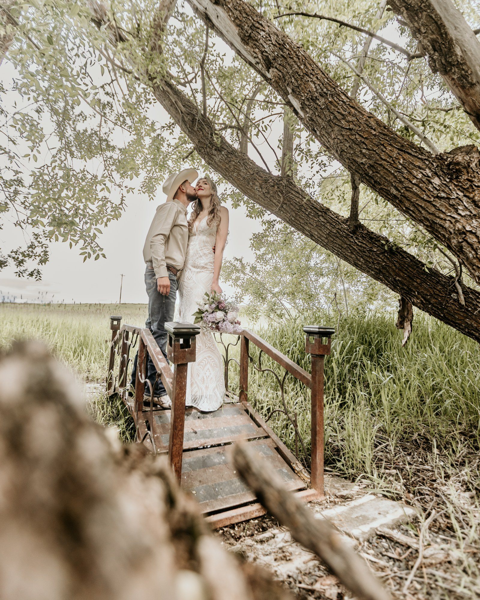 Couple on a wooden footbridge under a willow tree